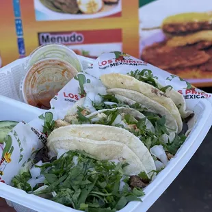 a hand holding a tray of tacos