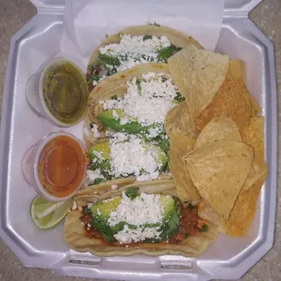 a variety of tacos in a styrofoam container