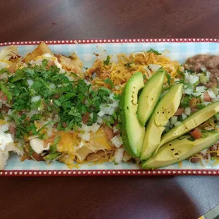 Tamales plate with rice and beans and avocado topped with pico onion cilantro and cheese