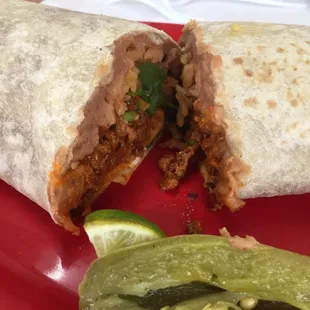 a burrito and pickle on a red plate