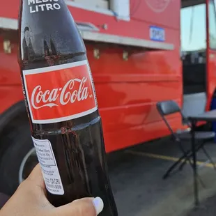 a hand holding a bottle of coca cola