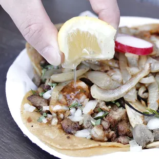 a person dipping a lemon wedge into a taco