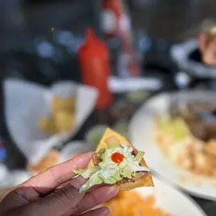 a hand holding a piece of pizza