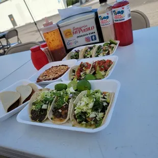 a table with tacos and salsa