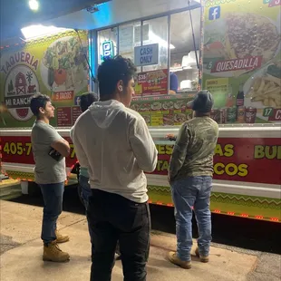 three men standing in front of a food truck