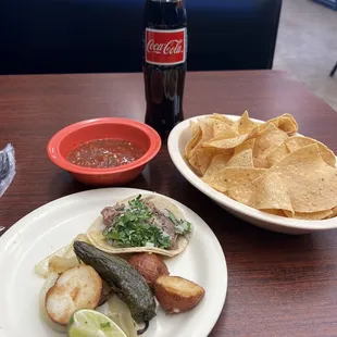 One carnitas taco with extra potatoes, chips and salsa.