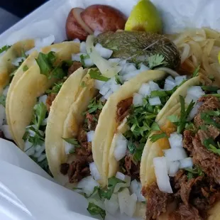 a tray of tacos with meat and onions
