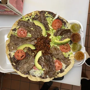 Tlayuda served with: chorizo, cecina meat, cabbage, Oaxaca cheese, avocado, tomatoes and black beans