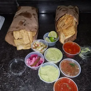 Taco bar with corn chips and flour chips with pickled onions, guacamole, limes, cabbage-jalepeno slaw, and spicy salsas!