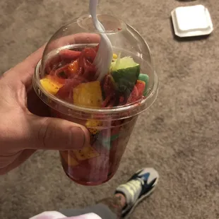 a person holding a plastic cup filled with fruit