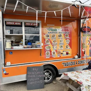 a man sitting at a table in front of a food truck