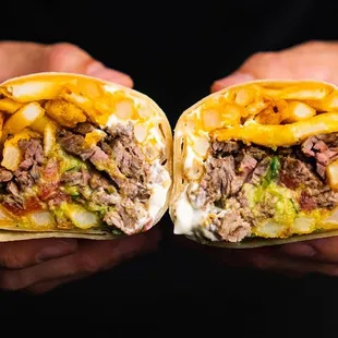 a man holding two burritos