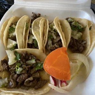 a variety of tacos in a styrofoam container