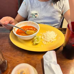 a young girl eating a bowl of soup