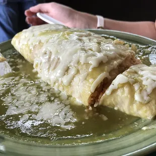 A rice, bean, and cheese burrito covered in green sauce.