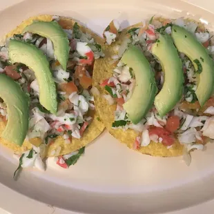 Tostadas Made with a flat hard shell corn  tortilla , shrimp, crab, onions, cilantro,  tomatoes and limes.