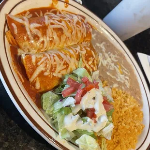 Chicken cheese enchiladas with a salad, rice and beans.