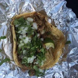 Carne asada taco in corn tortillas topped with onions and cilantro