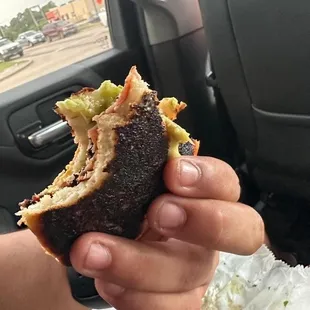a hand holding a half eaten sandwich