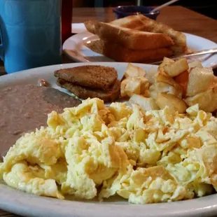 a plate of eggs, potatoes, and toast