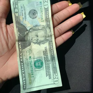  a hand holding a one hundred dollar bill