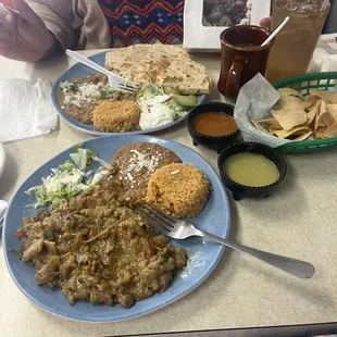 One plate is the Chicharrones plate with a salad, beans and rice and the other plate has Chicharrones quesadillas, salad, beans and rice.