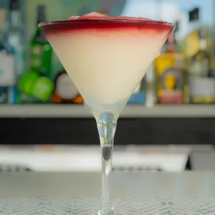 a red and white drink in a martini glass