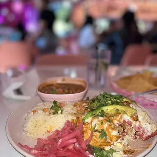 Chicken Enchiladas topped with an avocado cream paired with rice and beans.