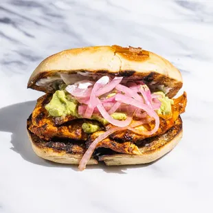 a chicken sandwich with onions and guacamole