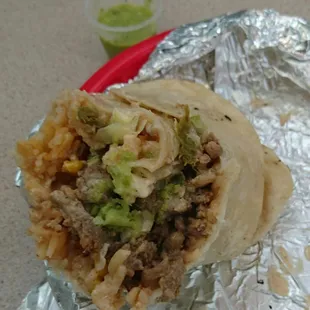 Half of burrito (carne asada) with their homemade tomatillo salsa