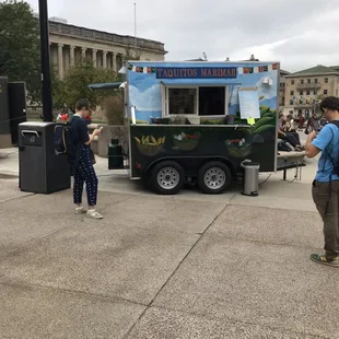 two people standing in front of a food truck