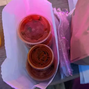 two cups of hot sauce on a picnic table