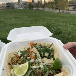 a person holding a container of tacos