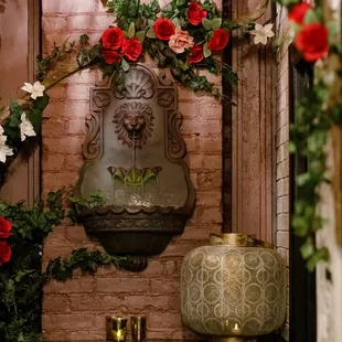 a wall fountain with roses and greenery