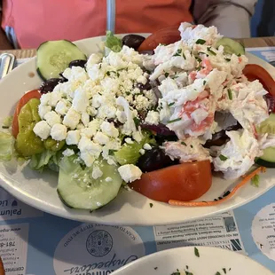 Greek salad topped with seafood salad