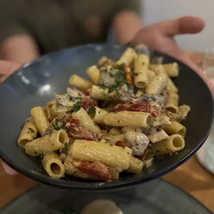 a person holding a bowl of pasta