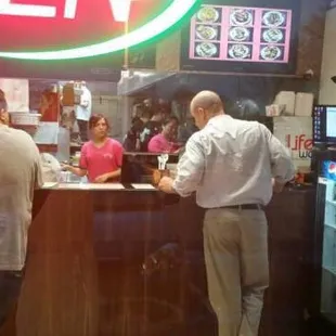 two men standing at a counter in a restaurant
