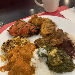 A mix from the buffet including chicken tikki masala, chicken tandoori, and goat curry.