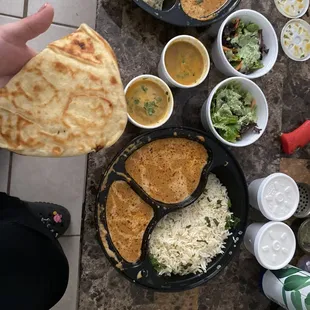 a person holding a piece of bread over a table full of food