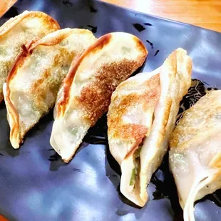 four dumplings on a black plate