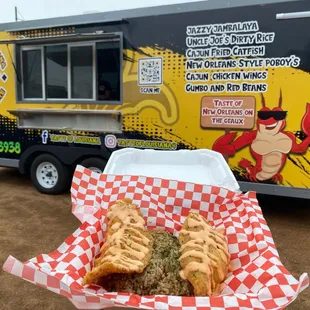 a hand holding a sandwich in front of a food truck