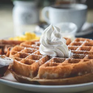 a plate of waffles with whipped cream