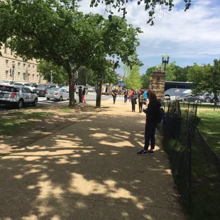 a woman standing on a sidewalk in a park