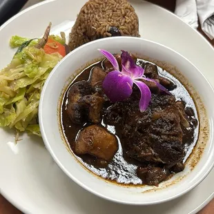 Jerk chicken with rice and peas with a side of fried plantain.