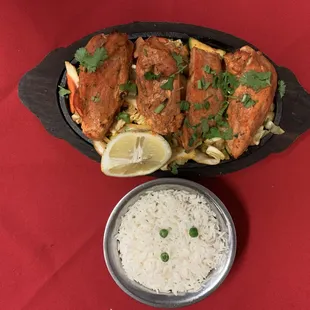 a fish dish with rice and lemon wedges