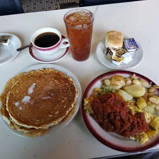 International omelet, short stack of pancakes, fried potatoes, coffee and iced tea.