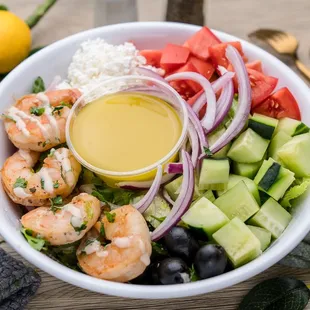 a salad with shrimp, cucumber, tomatoes, and onions