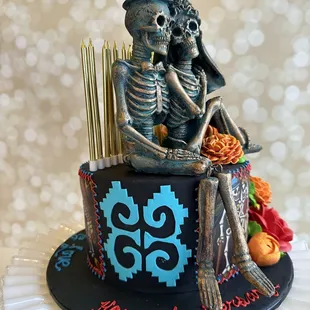 a skeleton couple sitting on top of a cake