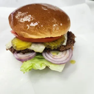 a hamburger with lettuce, tomato, onion, and cheese