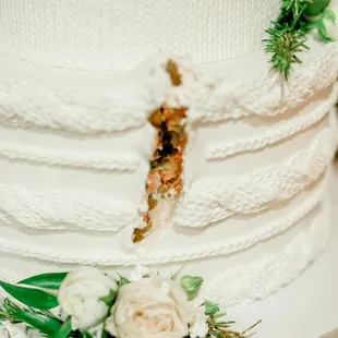 a white wedding cake with a slice taken out of it
